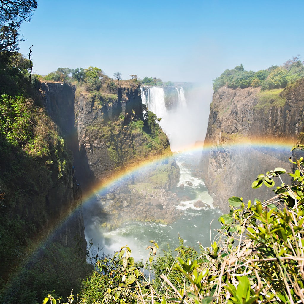 Ein Regenbogen über den Victoria Falls in Simbabwe